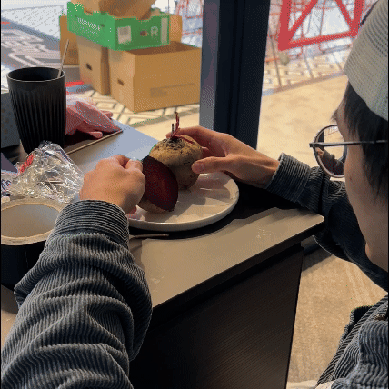 Person peeling a beet and a potato on a plate at a cafe table near a window.