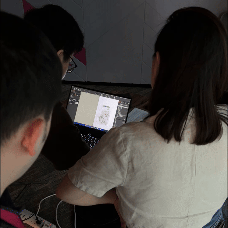 Three people working together on a laptop, looking at a design program.