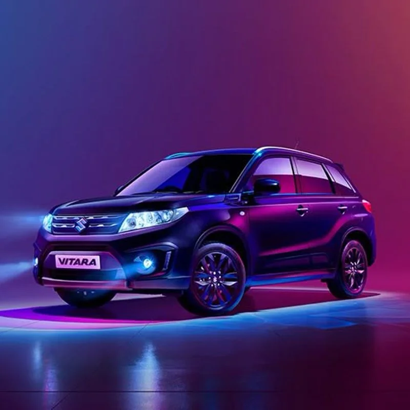 A sleek black Suzuki Vitara SUV illuminated with purple and blue lights, set against a colorful gradient background.