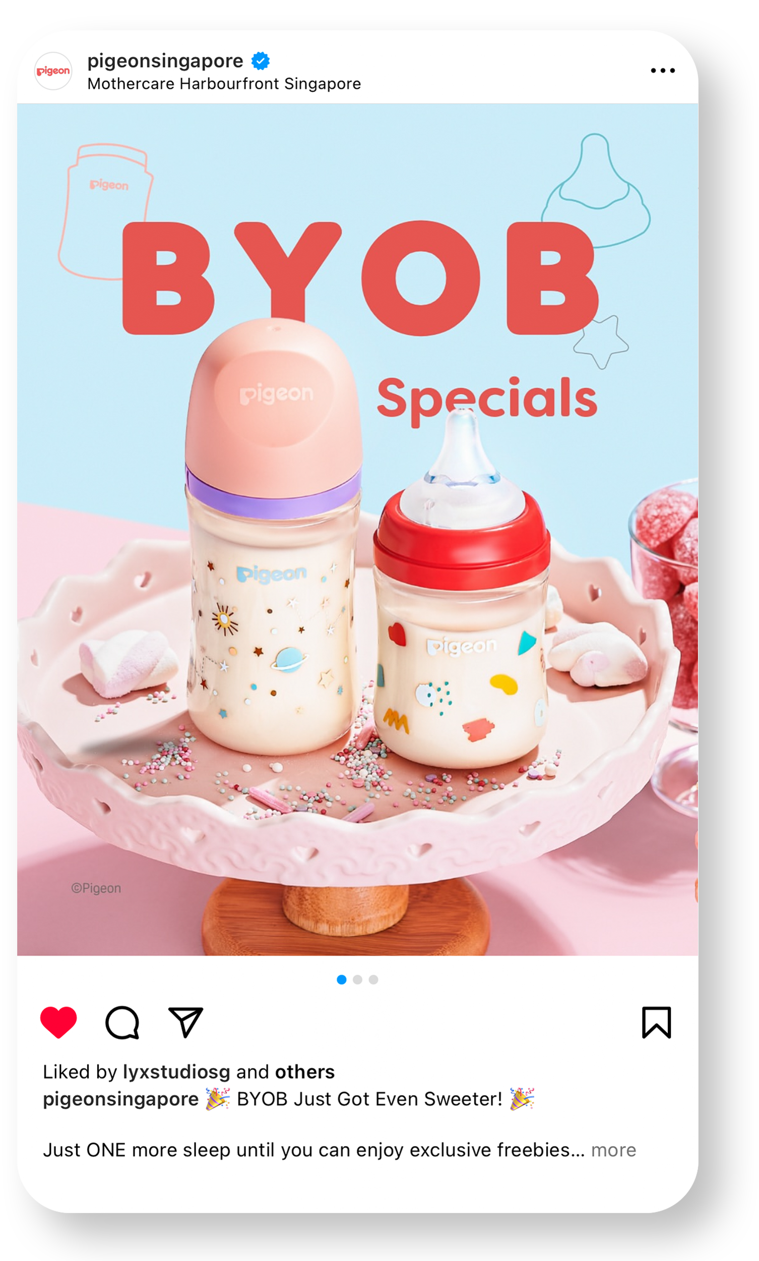 Two baby bottles with colorful celestial and abstract designs placed on a pink cake stand, surrounded by sprinkles and marshmallows. The background features a light blue wall with creative line drawings of baby items and bold red text that reads "BYOB Specials."