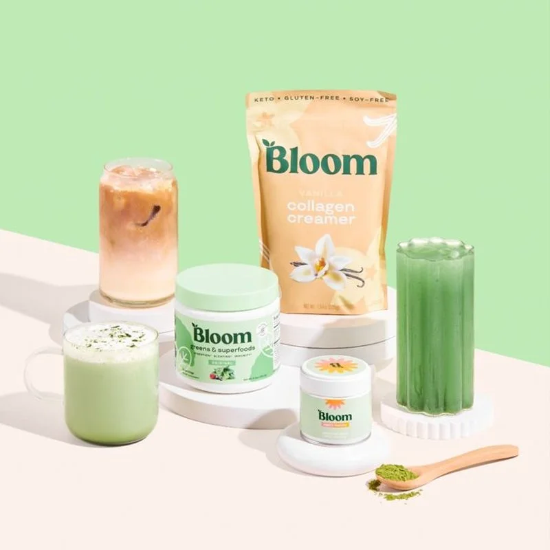 Several health and wellness products including a collagen cream packet, green superfood powder in a jar, a green drink, a layered iced tea, and a small bowl of green powder on a wooden spoon, arranged on a white surface with a pastel green background.