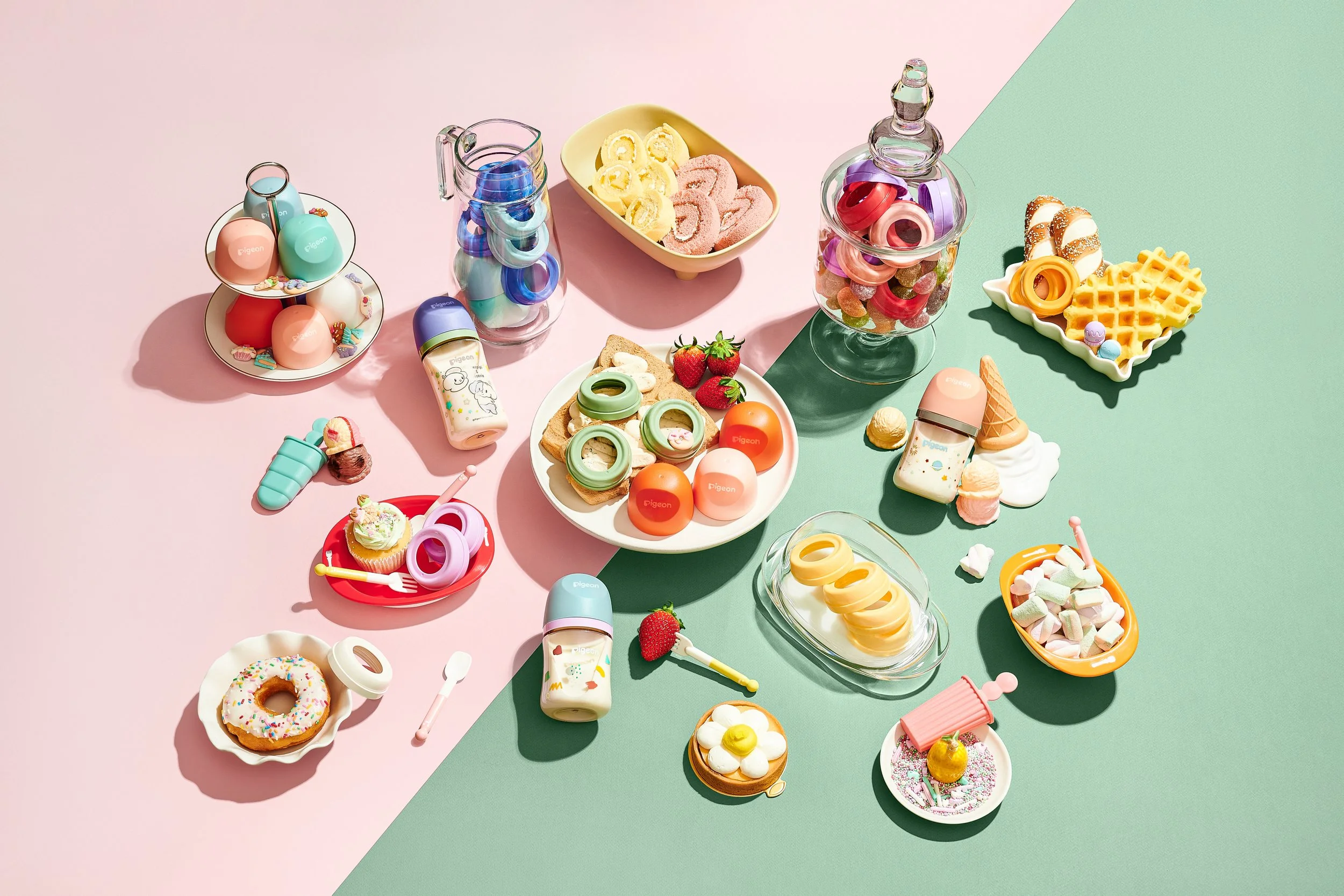 Colorful toy food and drink items arranged on pink and green backgrounds, resembling desserts, fast food, and snacks.