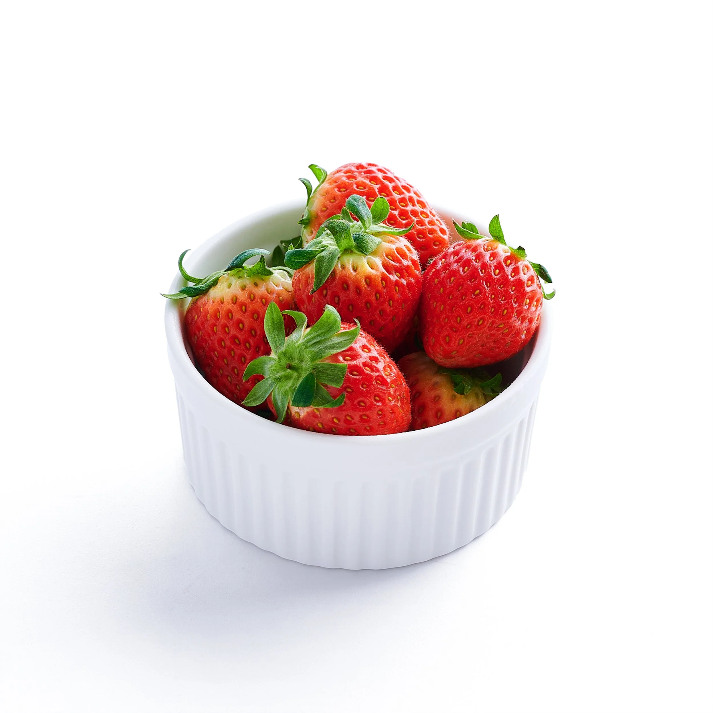 A white ceramic bowl filled with fresh, ripe strawberries on a white background.