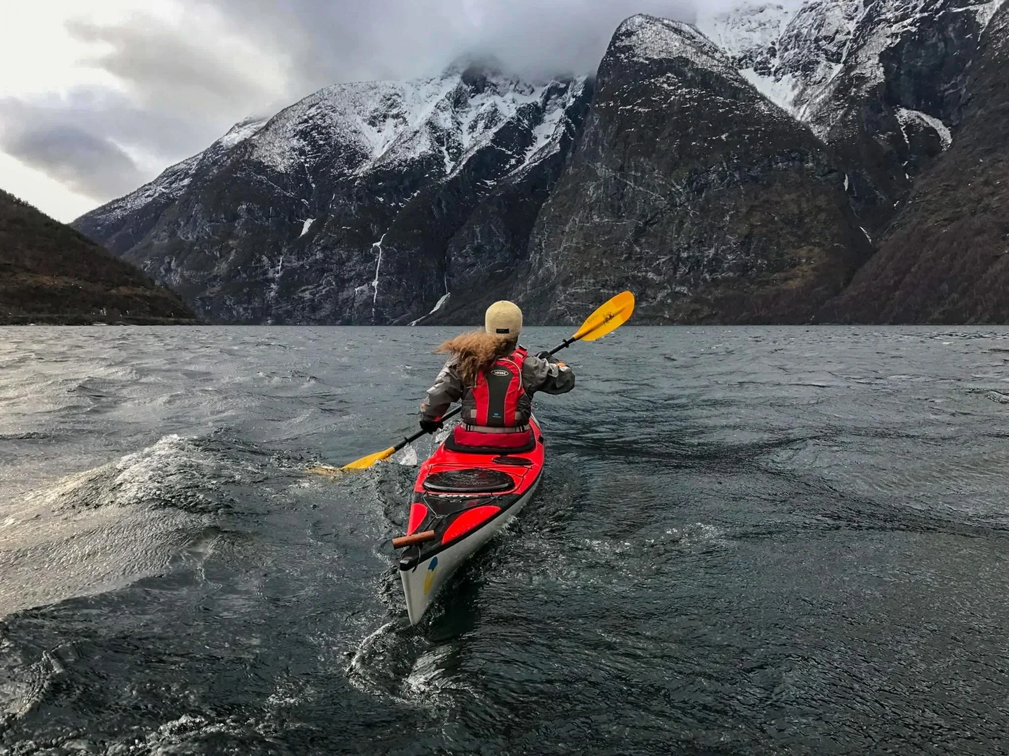 A paddleboarder glides across still waters with a mountain scene behind her
