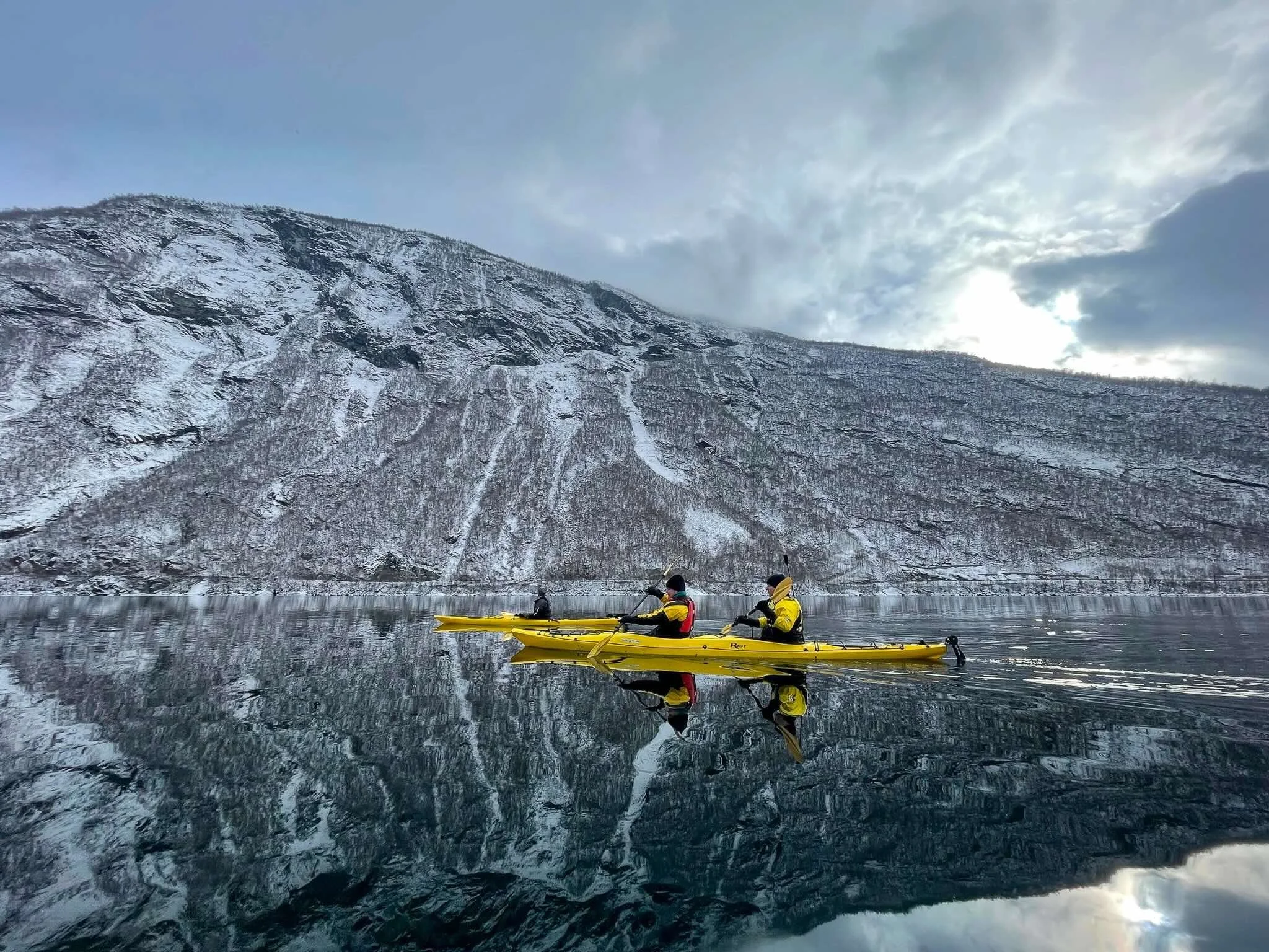 People Kayak across the bay in Lofoten
