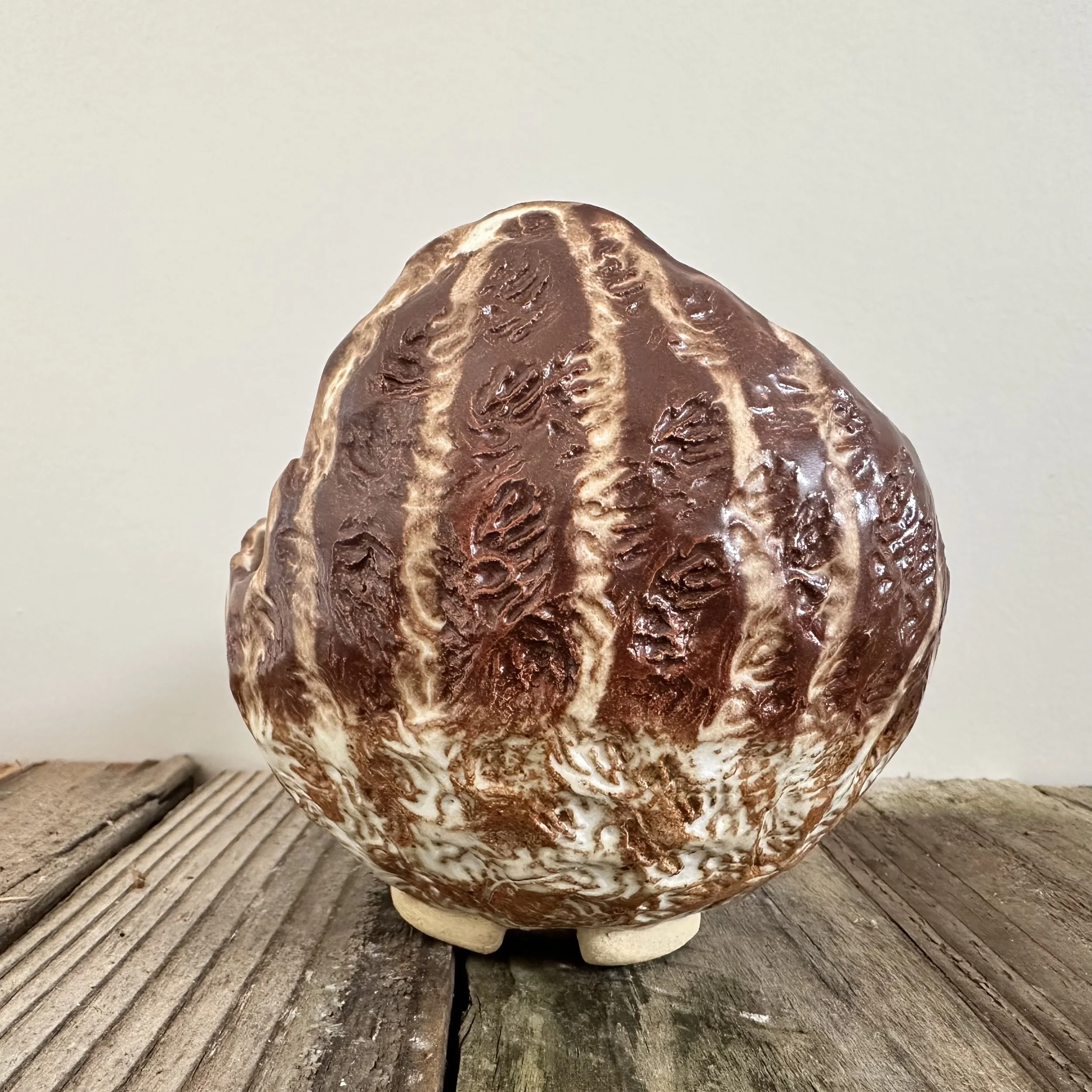 Brown textured ceramic sculpture on wooden surface