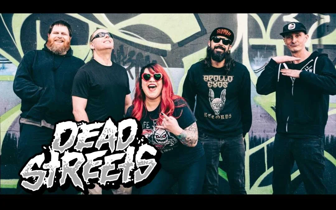 Group of five people standing in front of a graffiti wall, smiling and posing, with a "Dead Streets" logo overlay.