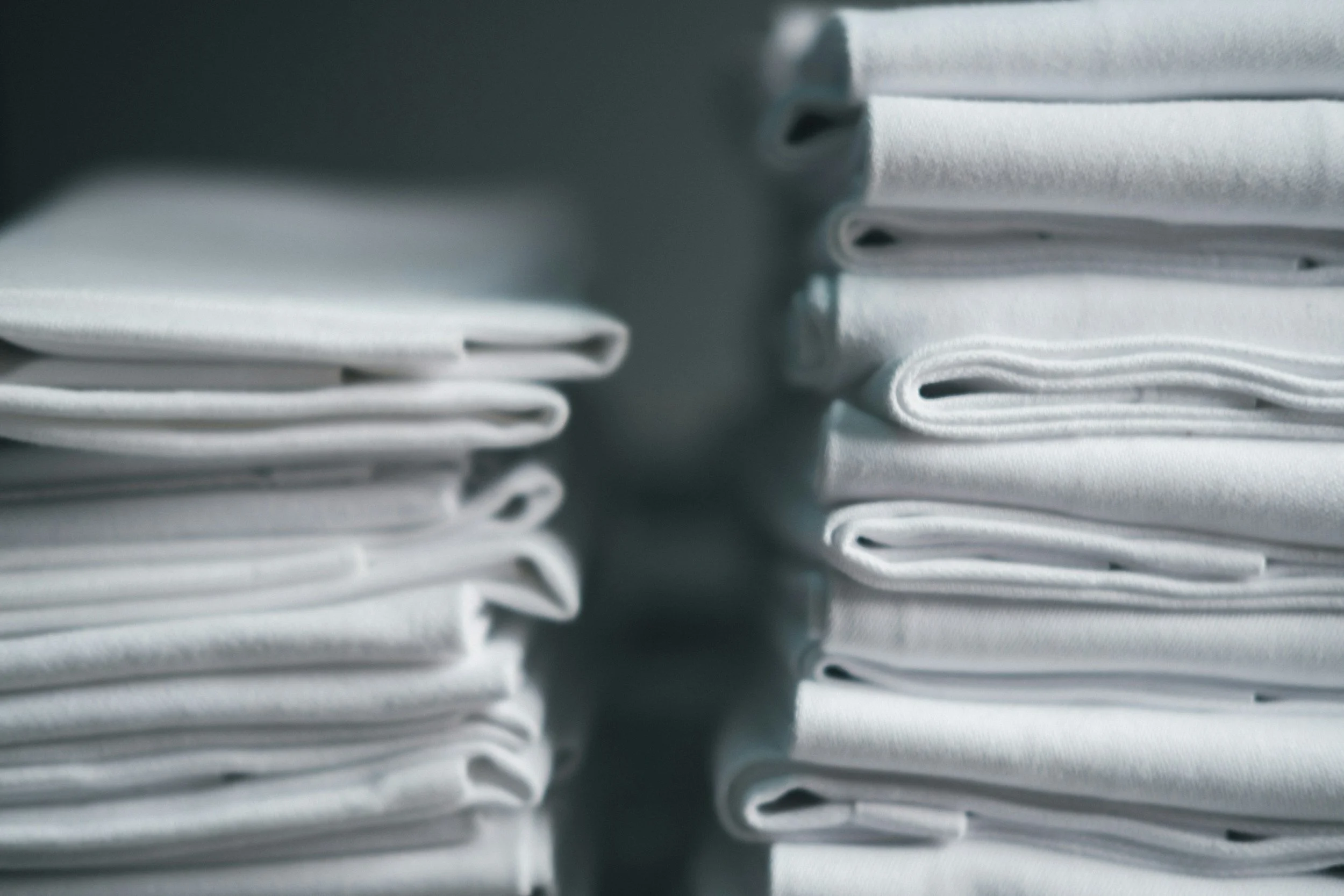 Close-up of neatly folded linen, possibly towels or sheets, stacked and organized for STRs and Boutique Hotels.