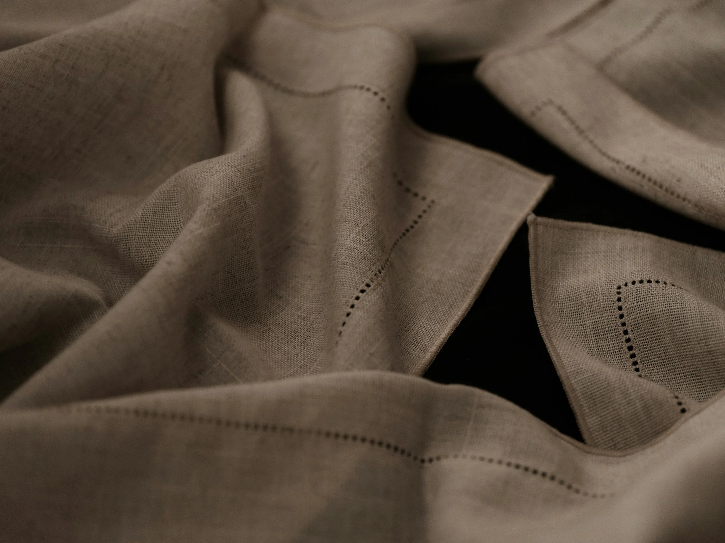 Close-up of beige fabric with black stitched dotted lines and cut-out sections.