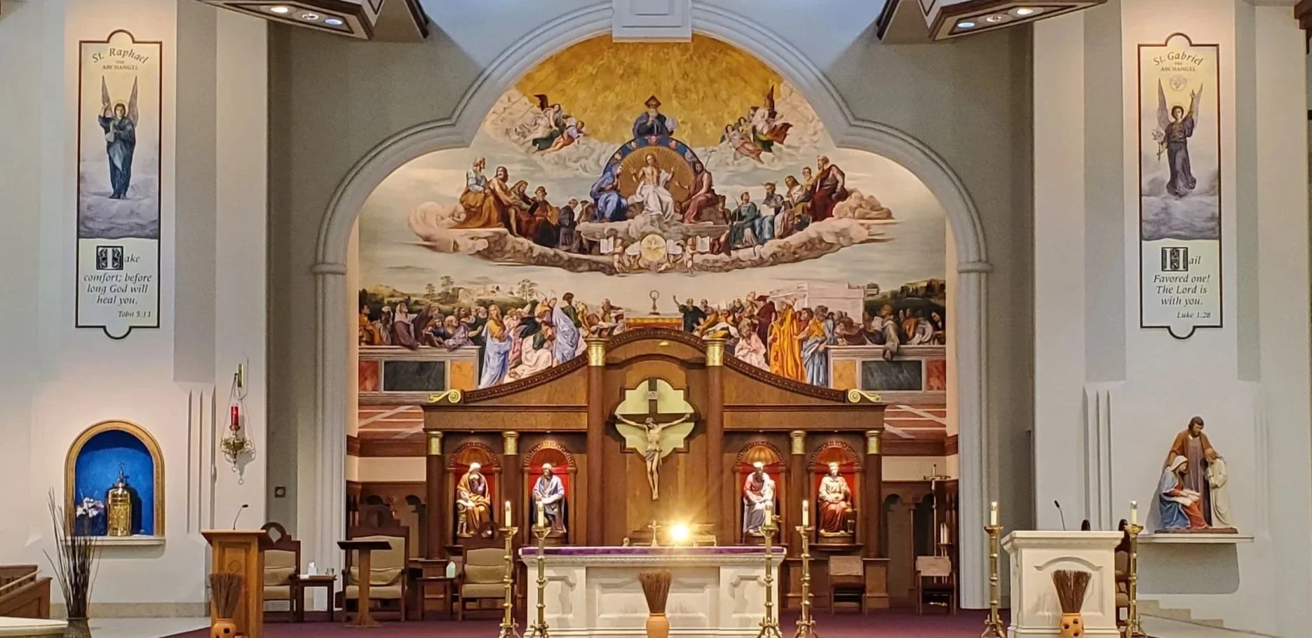 A wooden cross with a tattered cloth attached, set on rocky terrain during a sunset or sunrise.