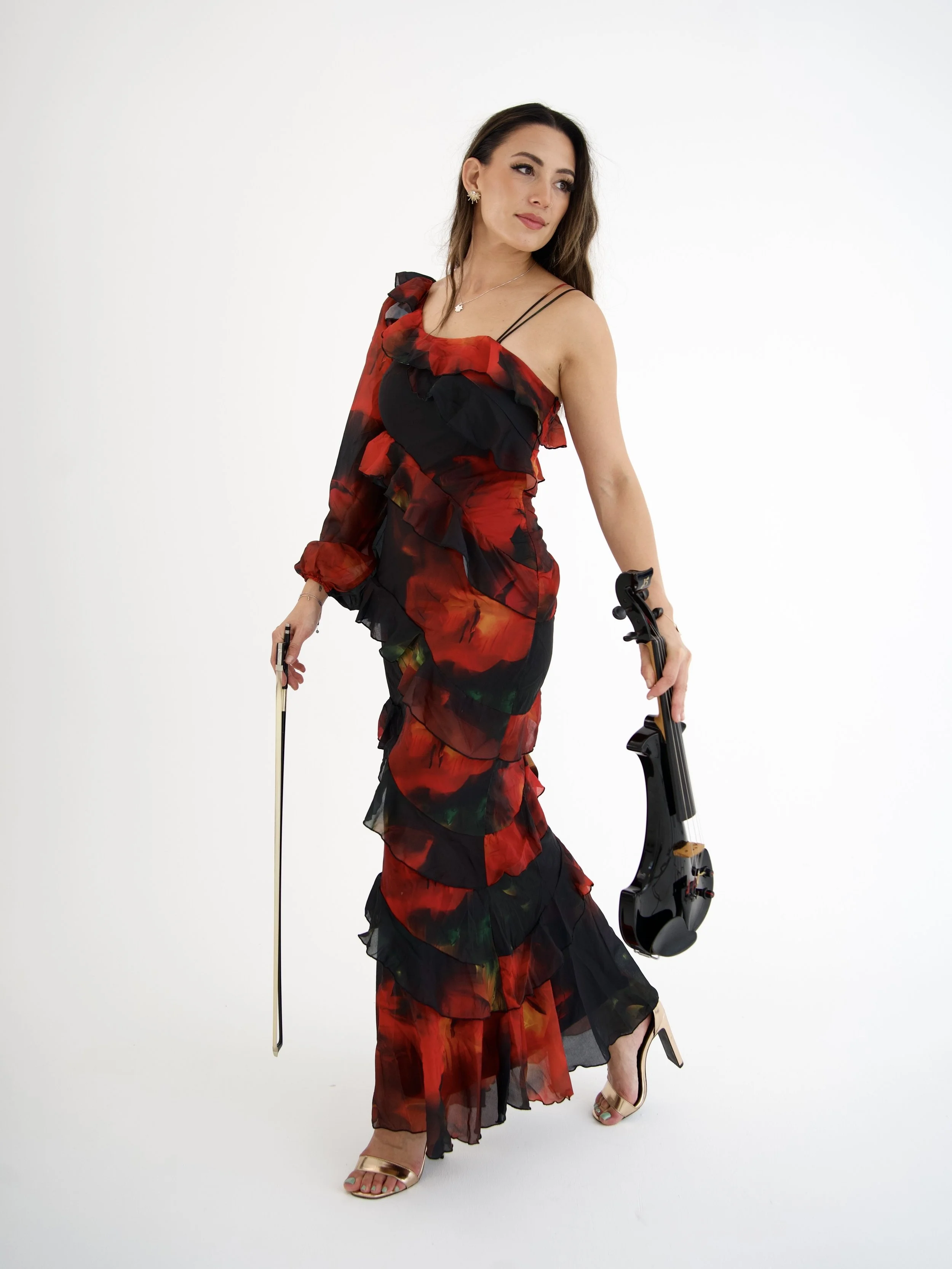 Ning-Ning in a black and red floral dress holding an electric violin against a plain white background.
