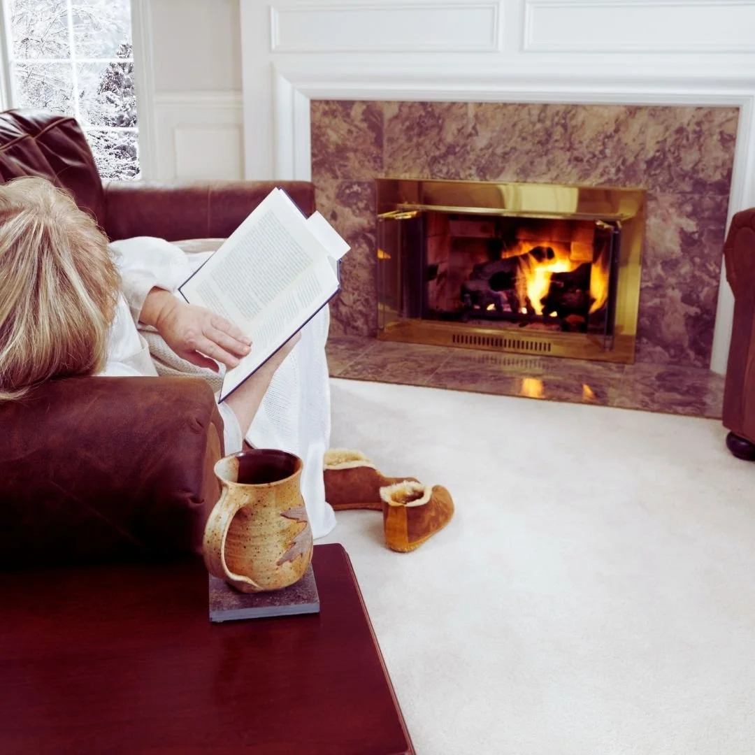 woman reading by fireplace in winter