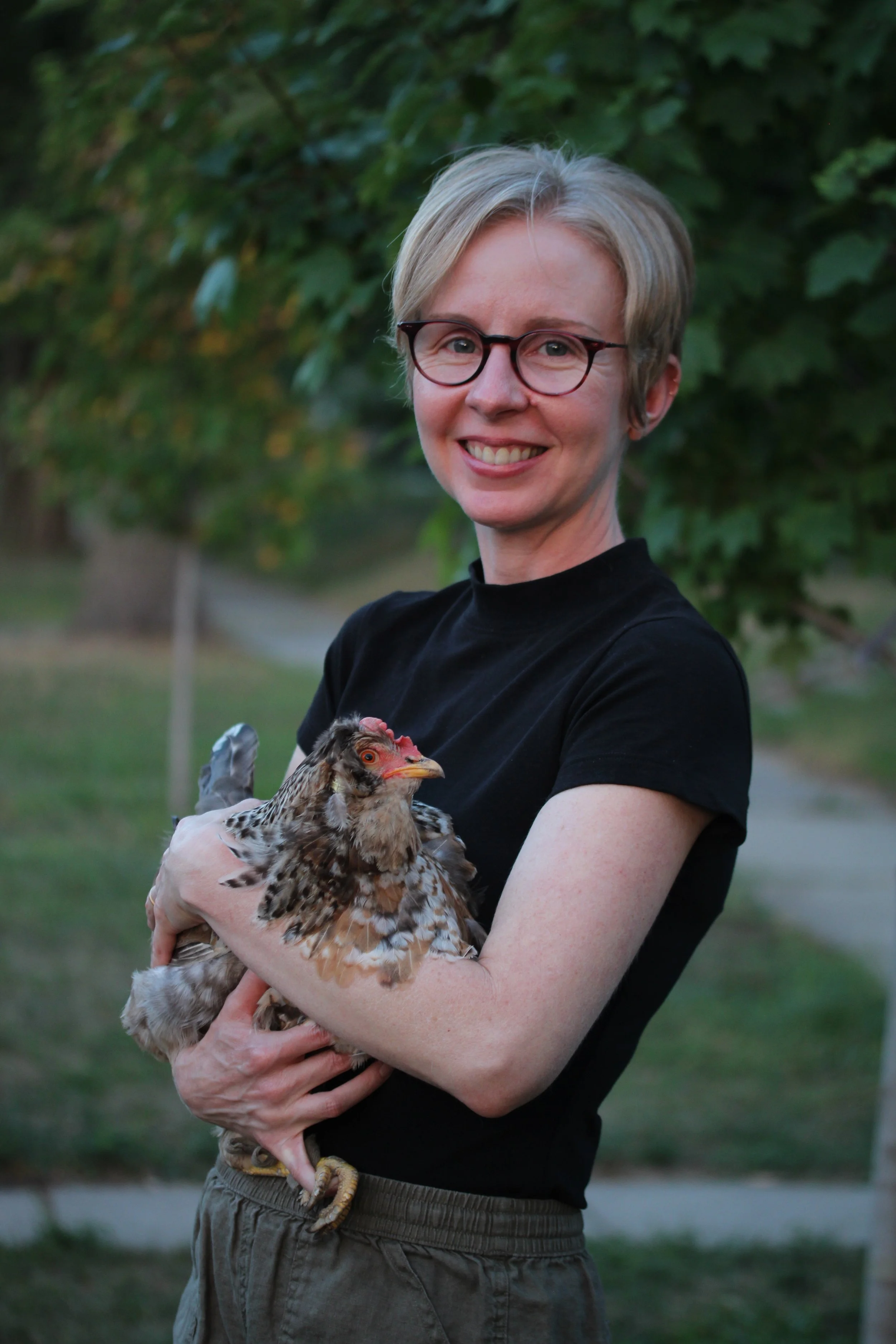 Rachel Kerr stands smiling at the camera while holding a live chicken in her arms.