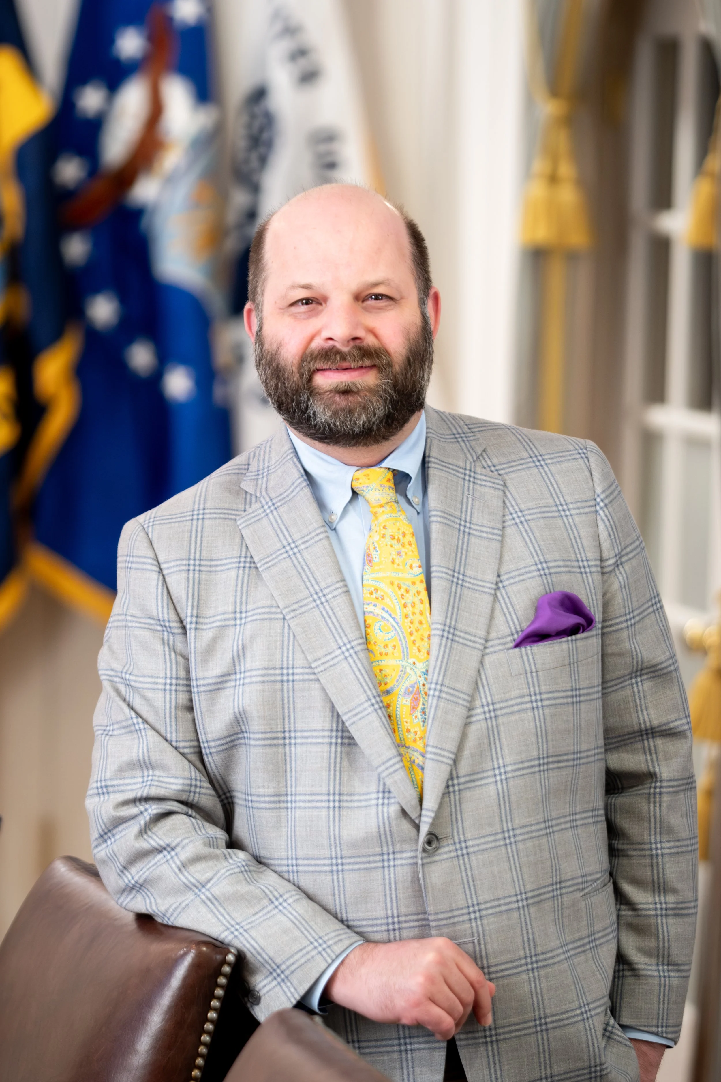 Man in a suit with striped tie and badge in front of a speckled wall