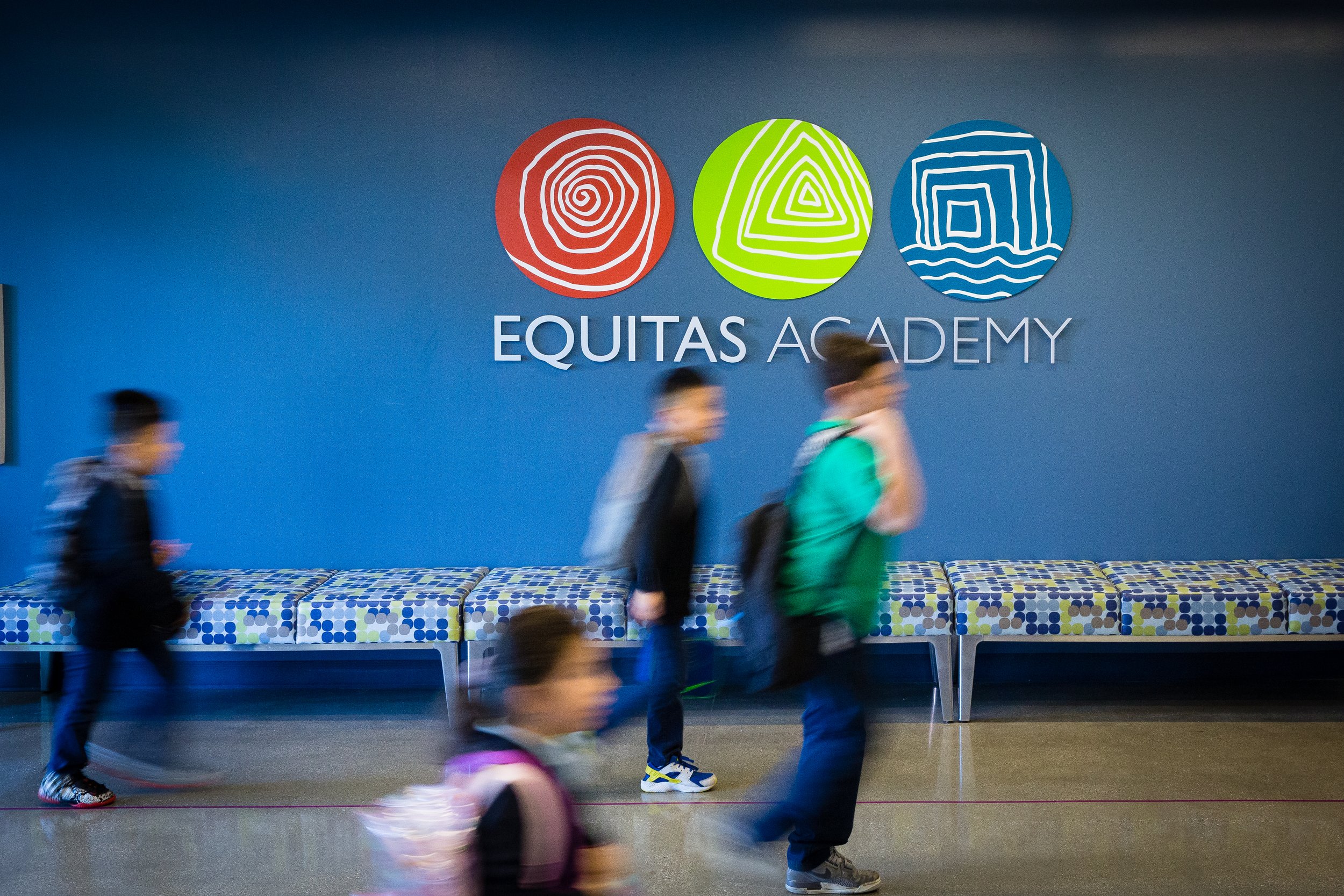 Students walking in front of a Equitas Academy logo sign