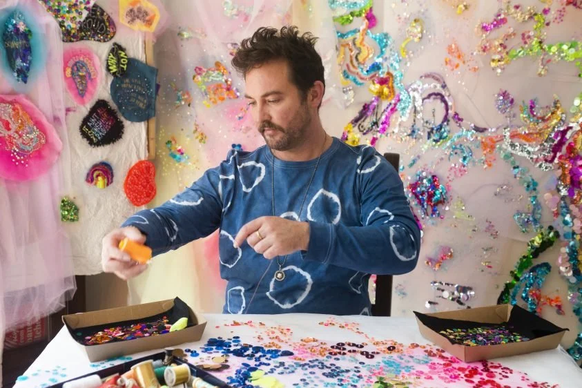 Artist sitting at table with paints in his hands