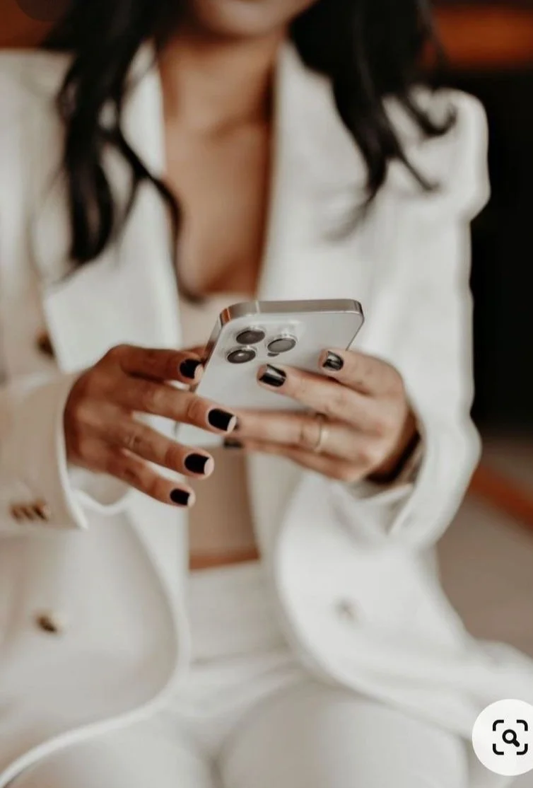 Person in a white suit holding a smartphone.