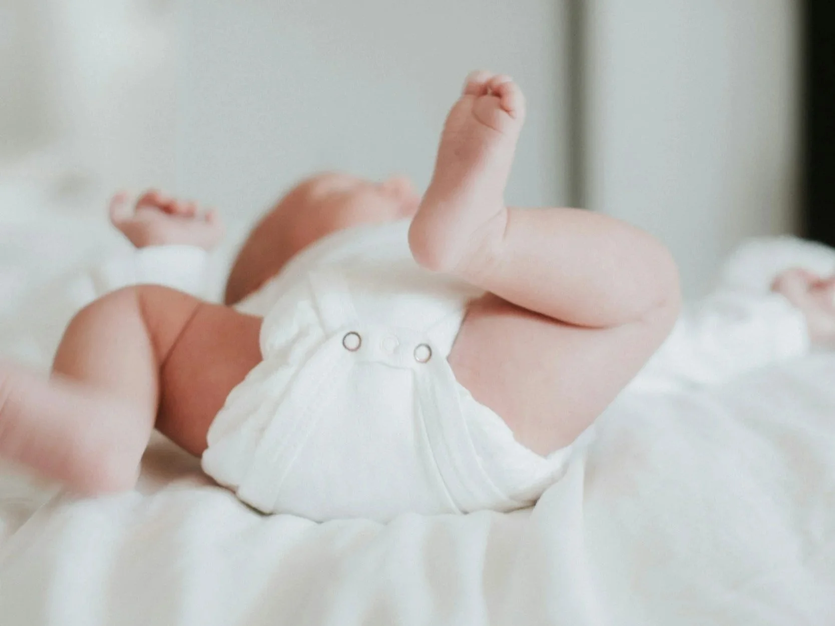 Newborn baby lying on back with legs lifted demonstrating early infant movement and core activation