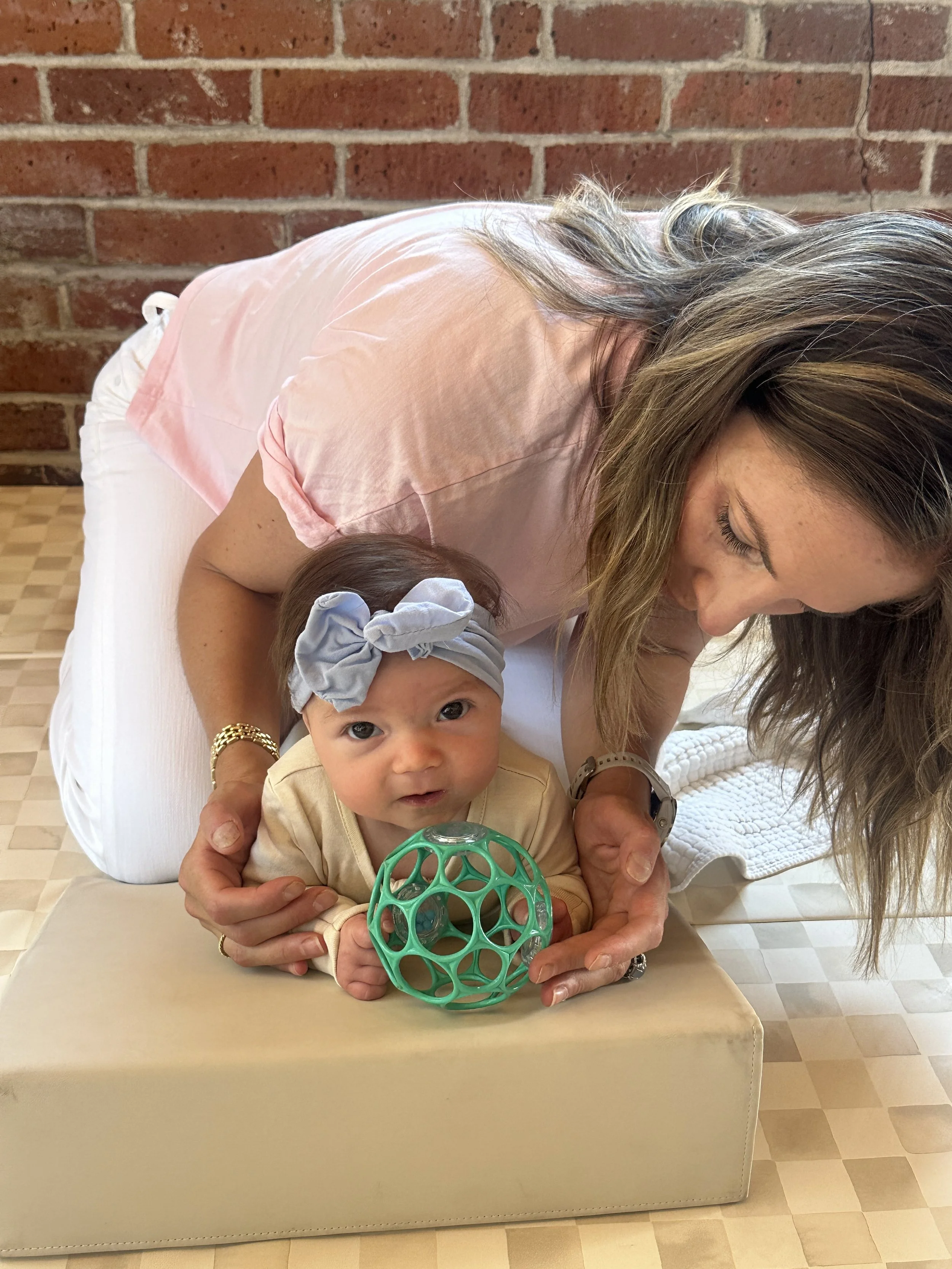 Dr. Nicole performing infant physical therapy with a baby during tummy time using a supportive foam wedge at Movevery in Denver, Colorado