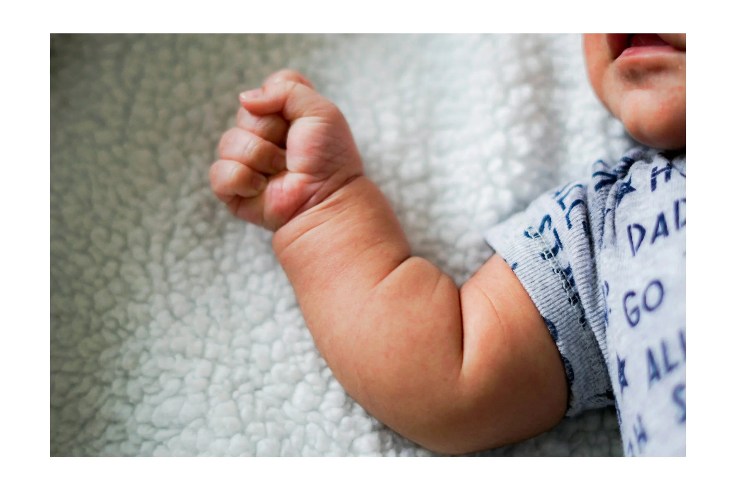 Newborn baby with clenched fist showing early infant tension and muscle tightness