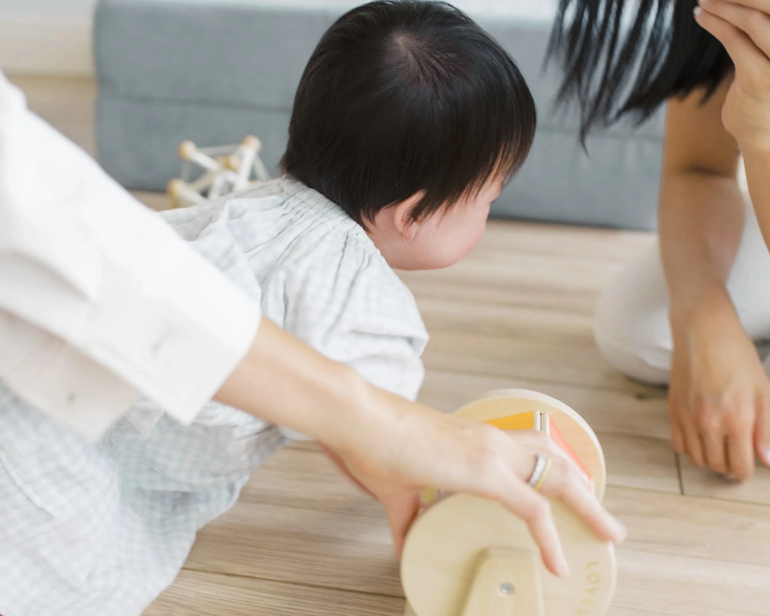 Baby on their tummy pivoting toward toys, building core strength and diagonal movement patterns for crawling.