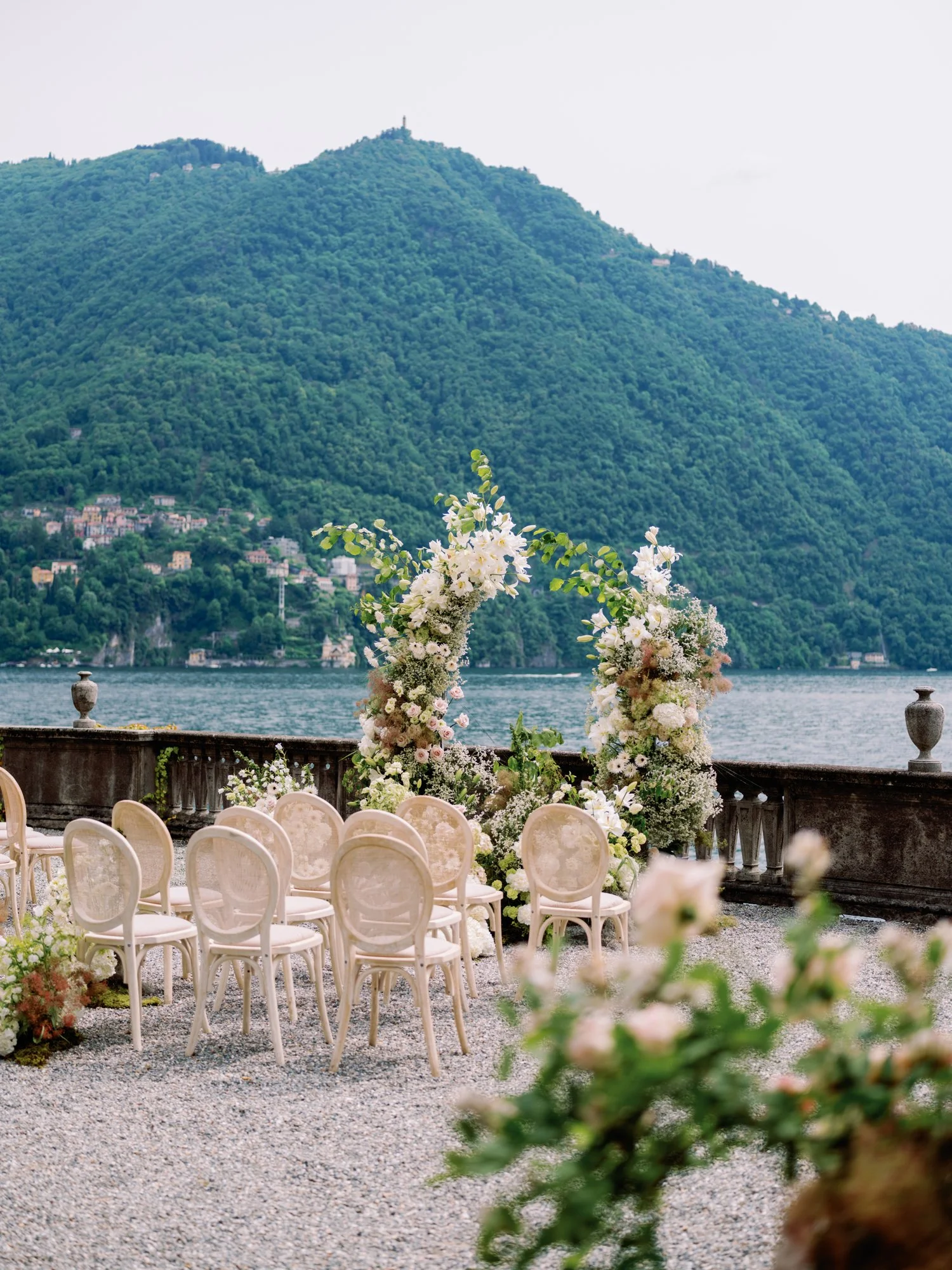 Floral arch and ceremony setup with beautiful flowers at Villa Pizzo Lake Como in Italy against the water