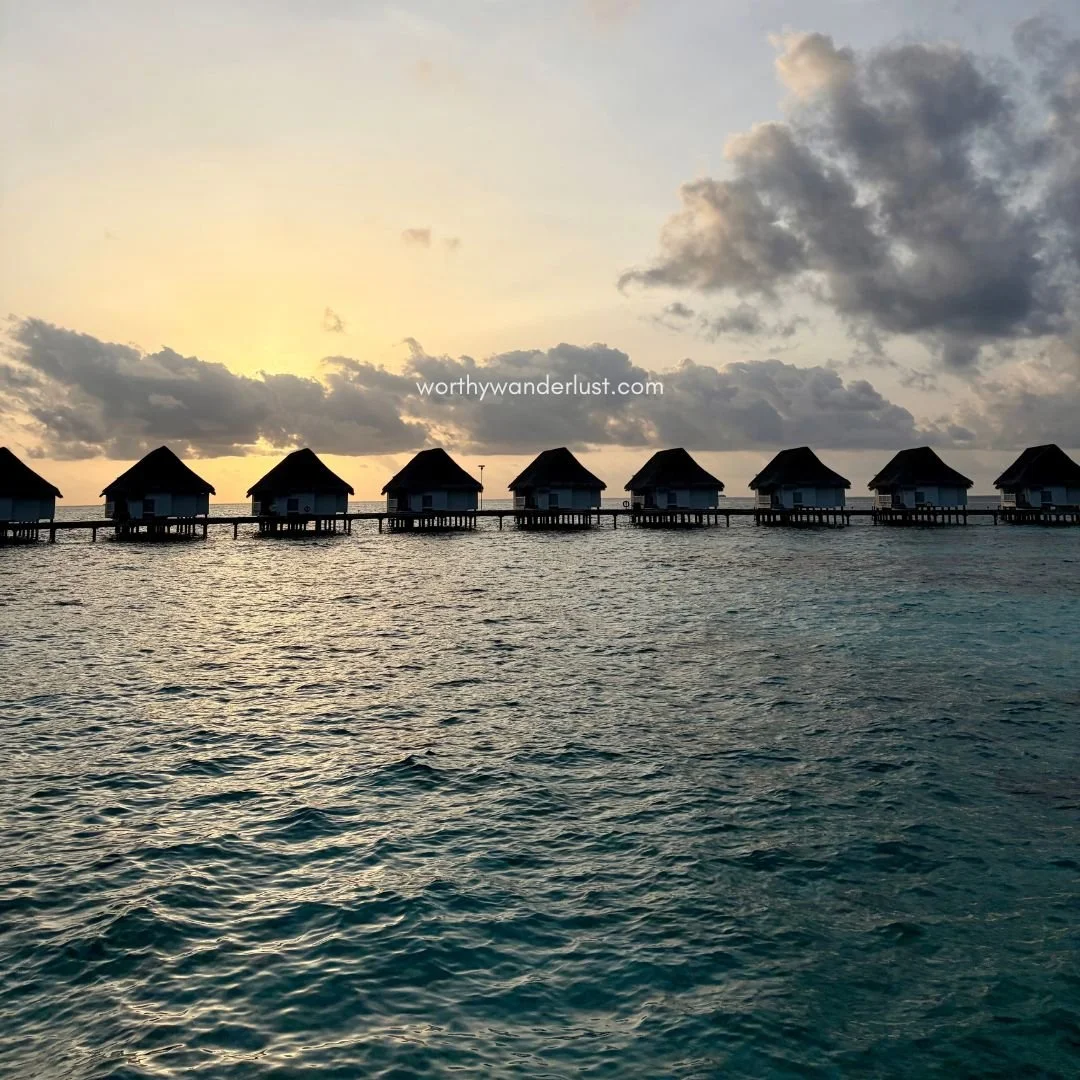 A beautiful sunset above overwater villas and ocean