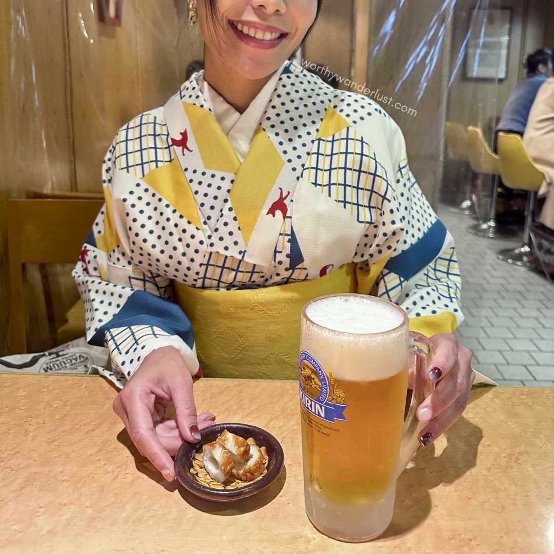 Founder of Worthy Wanderlust ina kimono, having a pint of beer and a snack. in a restaurant in Kurashiki.