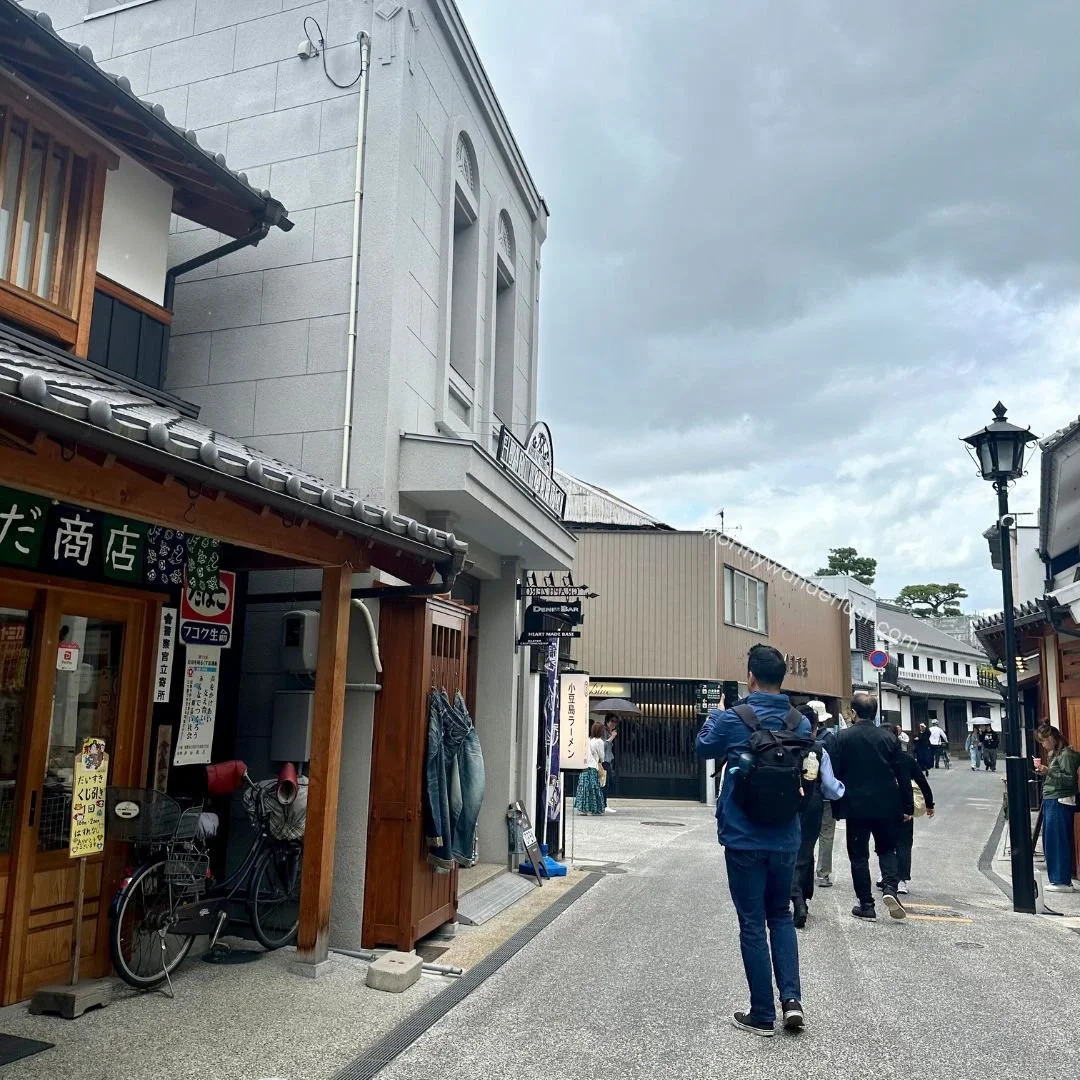 A man taking  a photo outside Heart Made Base in Kurashiki Bikan Historical Quarter
