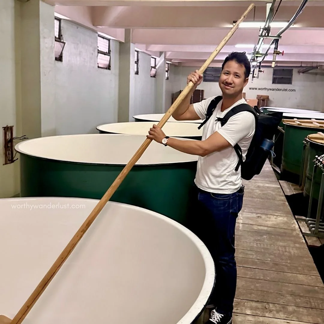 Worthy Wanderlust founder's partner holding sake brewing equiptment at Morita Brewery in Kurashki
