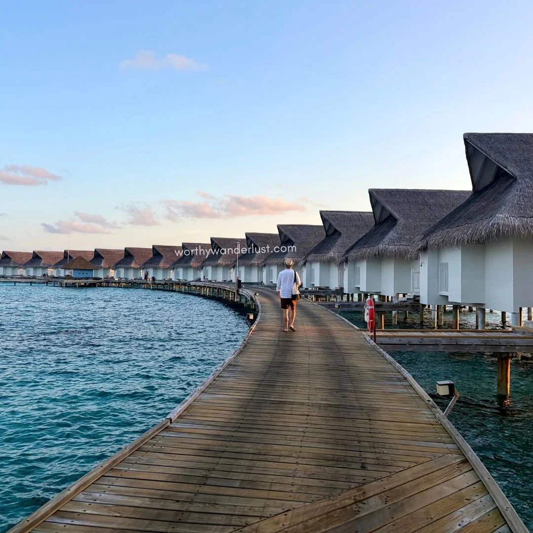 Man walking along a boardwalk to a stretch of overwater villas in Maldives