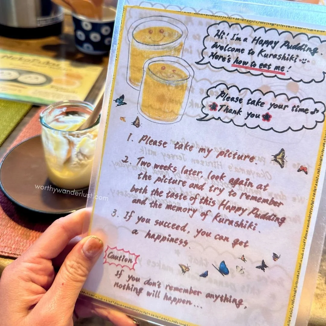 Hand holding up printed guidelines for eating happy pudding in Kurashiki Yuurin-an