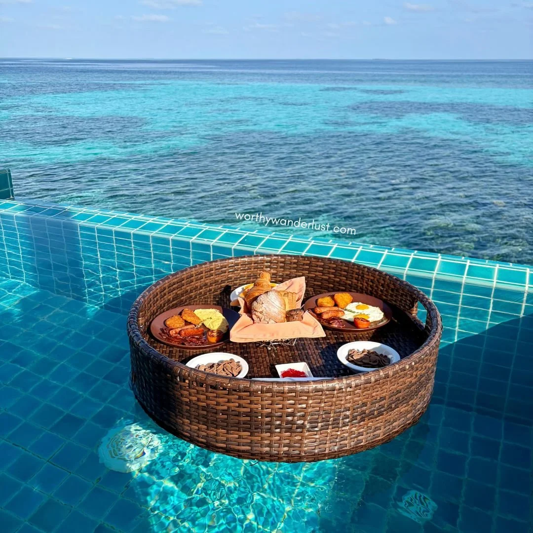 Floating breakfast basket, with complete breakfast, pastries and cereal, on a small plunge pool with an ocean view.