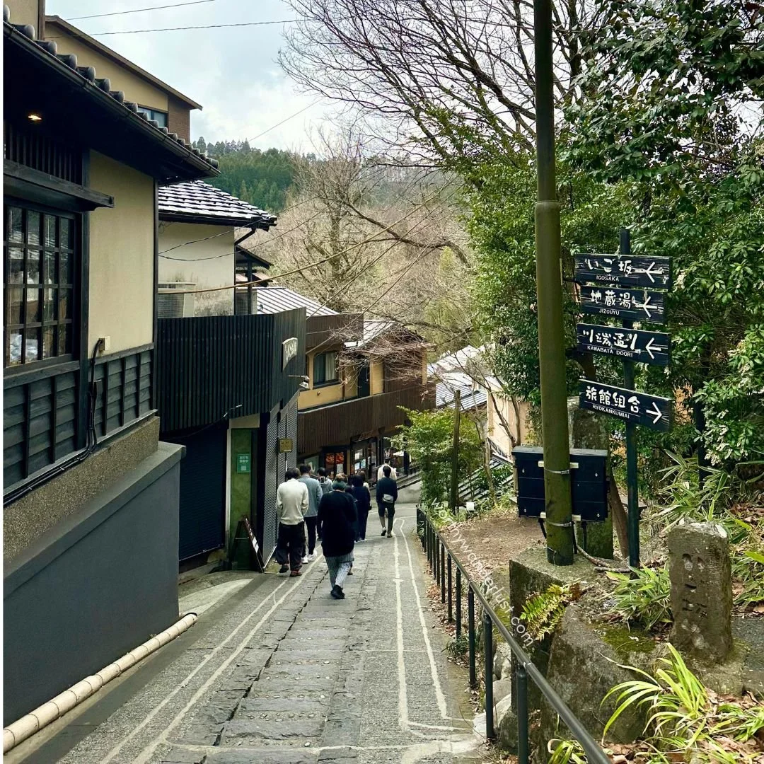 Sloped walking path with traditional houses and greenery at the sides in Kurokawa Onsen