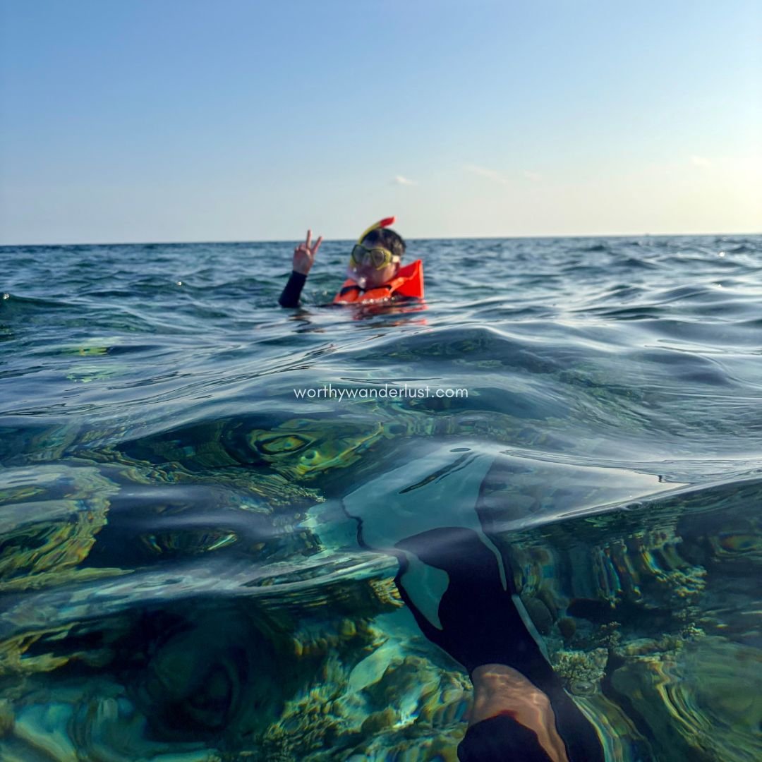 Man with peace sign and snorkel gear in the ocean, at Machchafushi house reef.