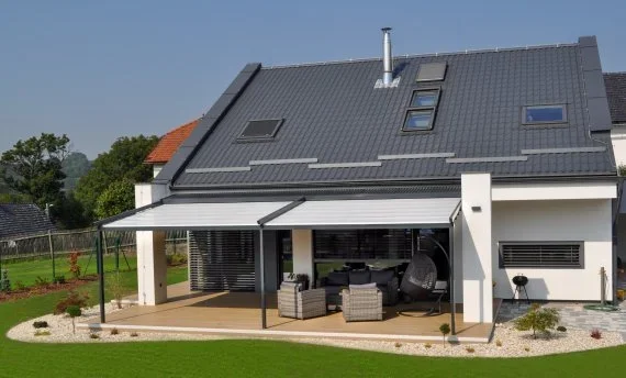 Látková pergola s poťahom z pevného PVC na terase moderného rodinného domu.