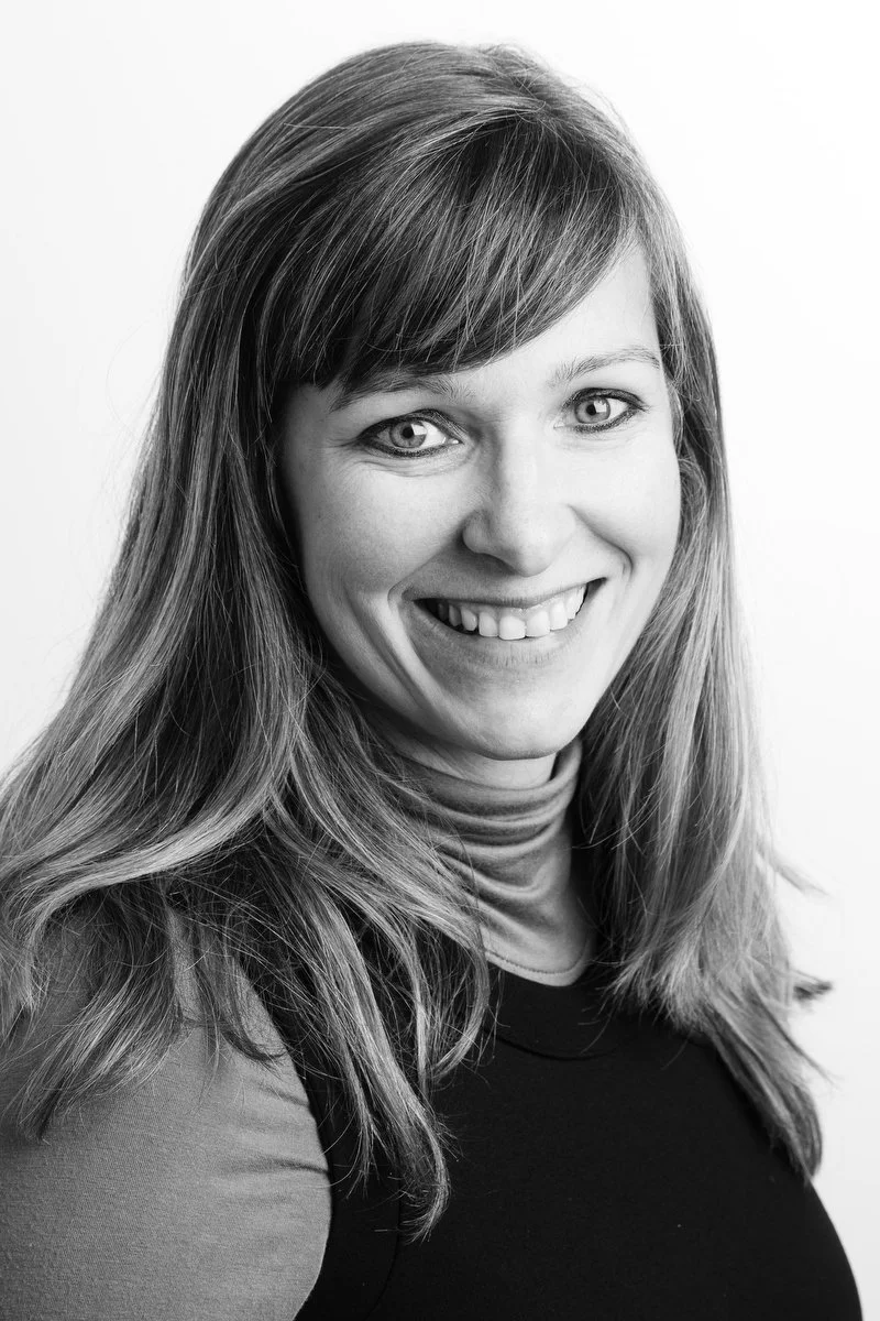Portrait en noir et blanc d'une femme souriante aux cheveux longs et au col roulé.