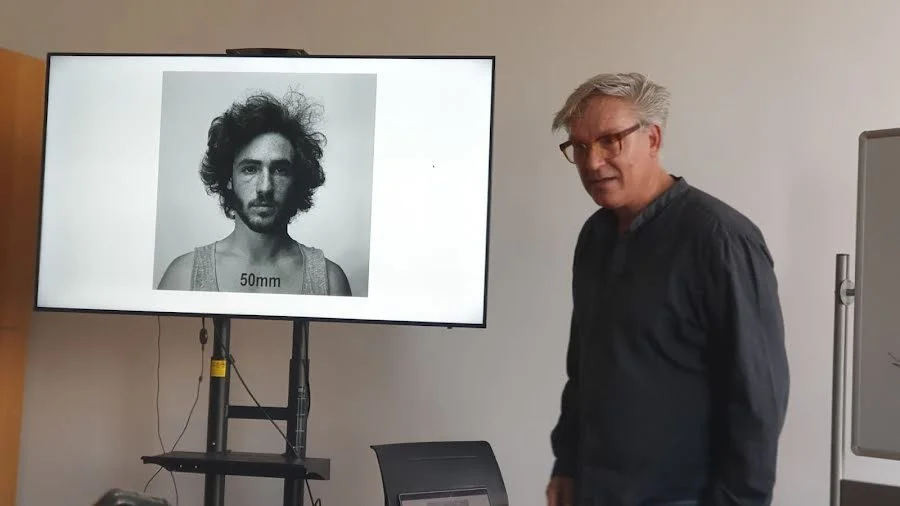 photographer and teacher in Brussel Sander next to a screen with a portrait of a man while doing a photography workshop