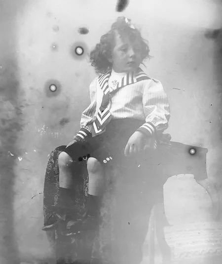 un garçon assis pour un portrait en noir et blanc pris avec un très vieil appareil photo