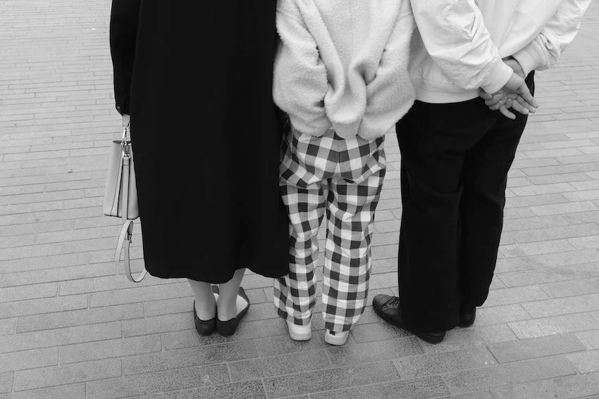 Black and white picture of three people standing, only legs shown