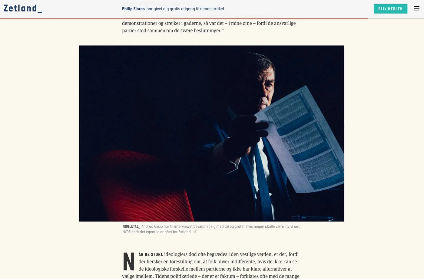 Homme en costume tenant un papier avec des graphiques, sous un faible éclairage, sur un fond sombre.