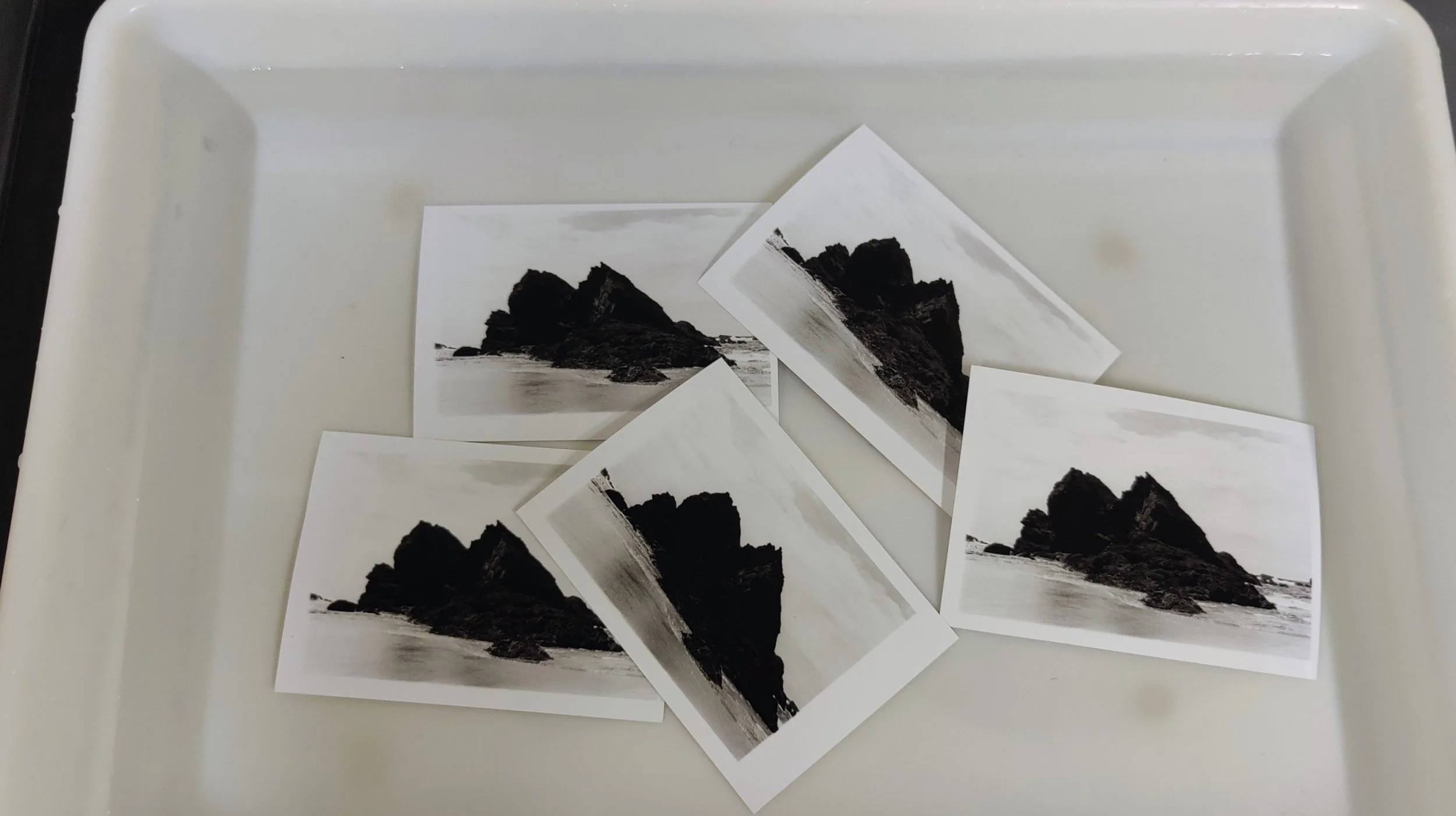 4 pictures of mountains floating in a bath in a photographic darkroom during the photo workshop