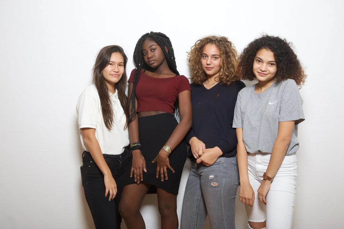 portrait photography of Four young women posing together against a plain white background.