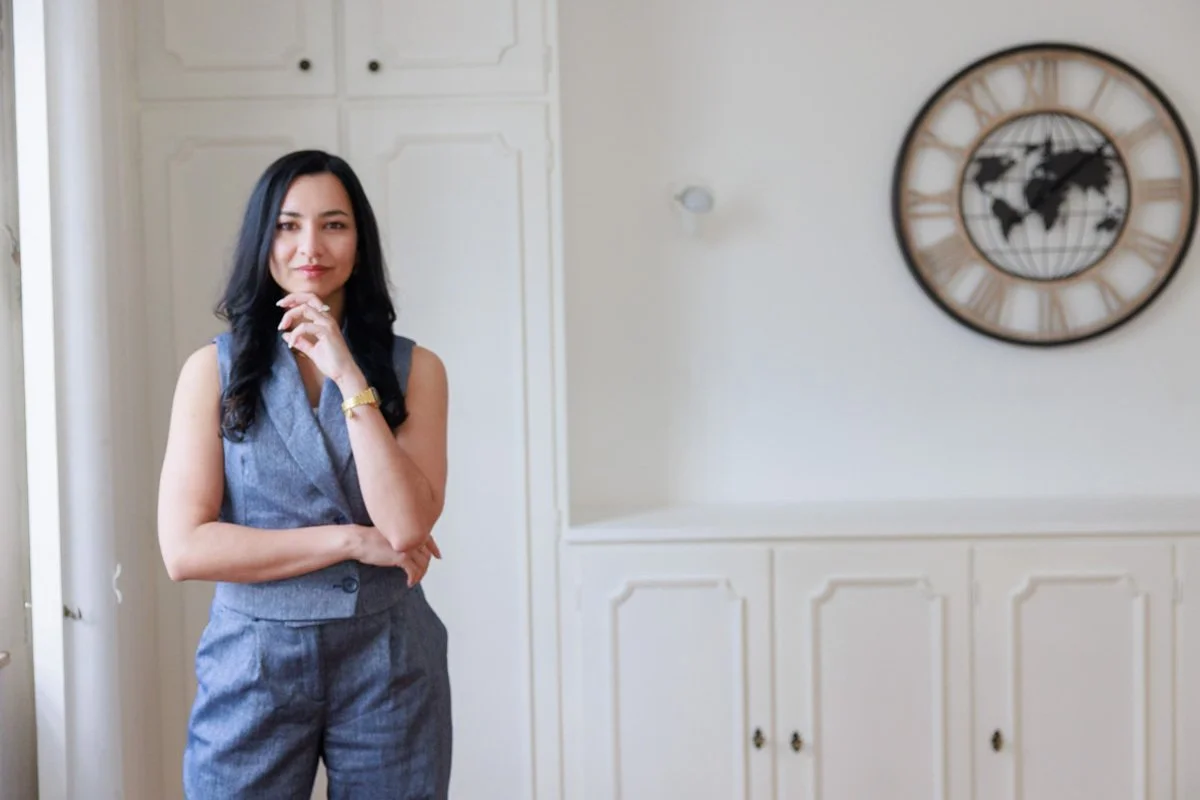 Corporate Portrait  of a Woman in professional attire standing beside a wall with a world map clock.