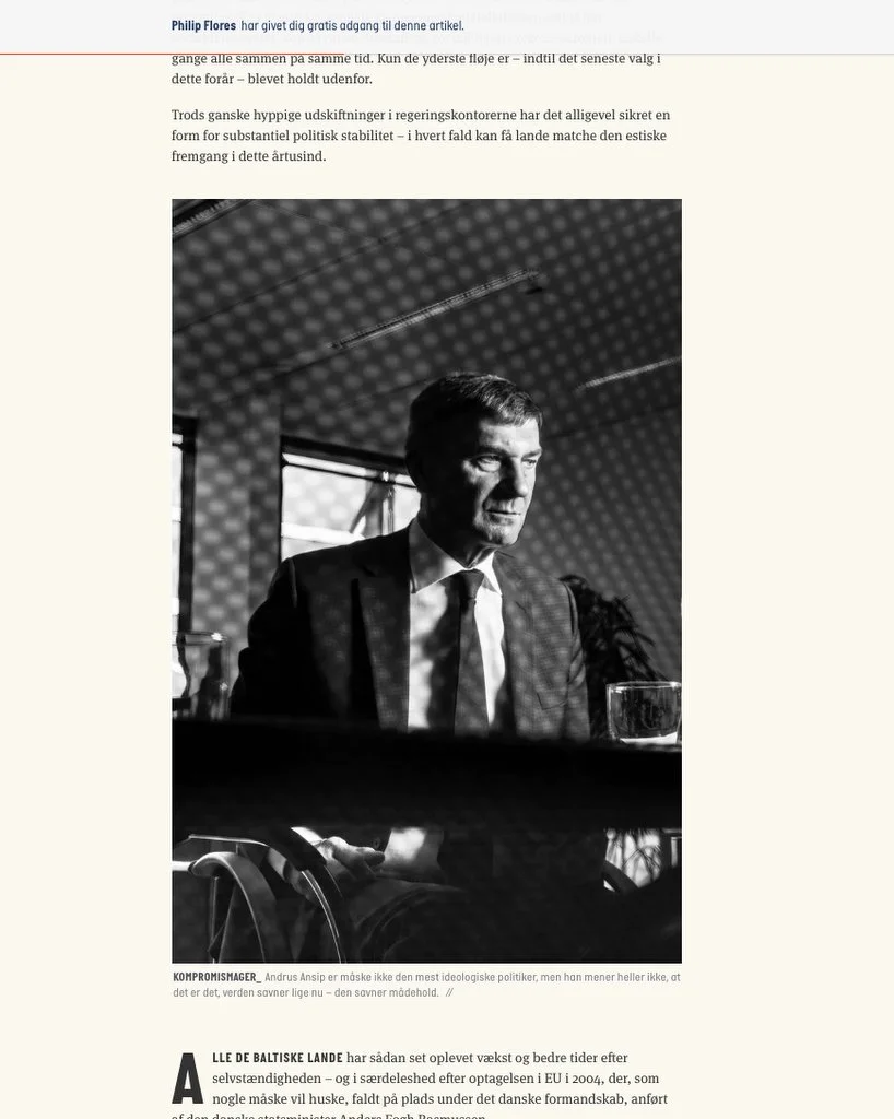 Photo en noir et blanc d'un homme en costume assis à une table, avec une ombre projetée sur lui. Un texte en danois décrit ses positions politiques.