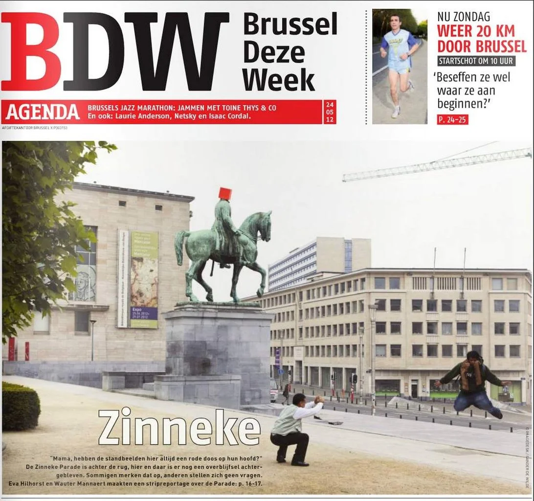 Couverture du magazine BDW représentant la statue d'un cavalier avec une boîte rouge sur la tête et un homme sautant devant lui, avec des bâtiments de la ville en arrière-plan.