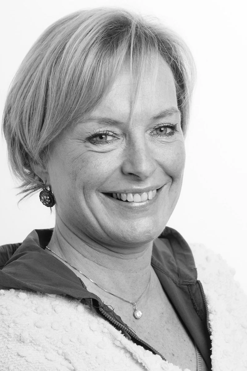 Portrait d'une femme d'âge moyen souriant en noir et blanc.