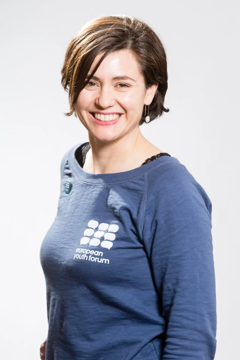 Personne souriante, portant une chemise bleue "Forum européen de la jeunesse".