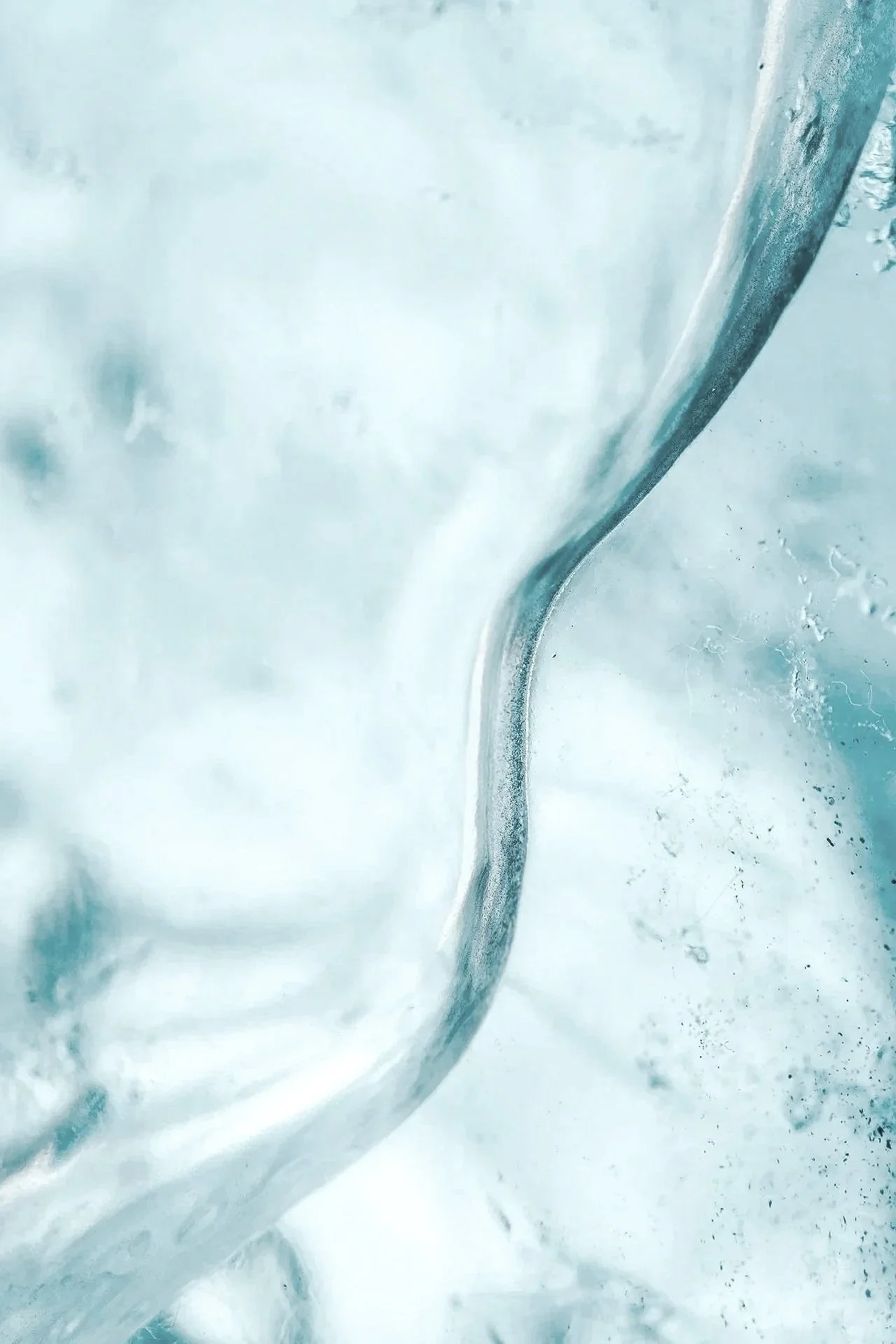 Close-up of a glass of water being poured, ice visible inside the glass.