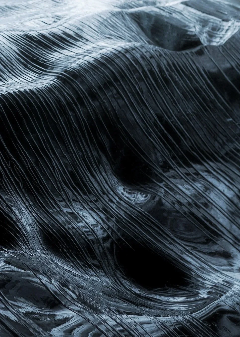Close-up of black plastic sheeting or tarpaulin with shiny, curved, and wrinkled texture.